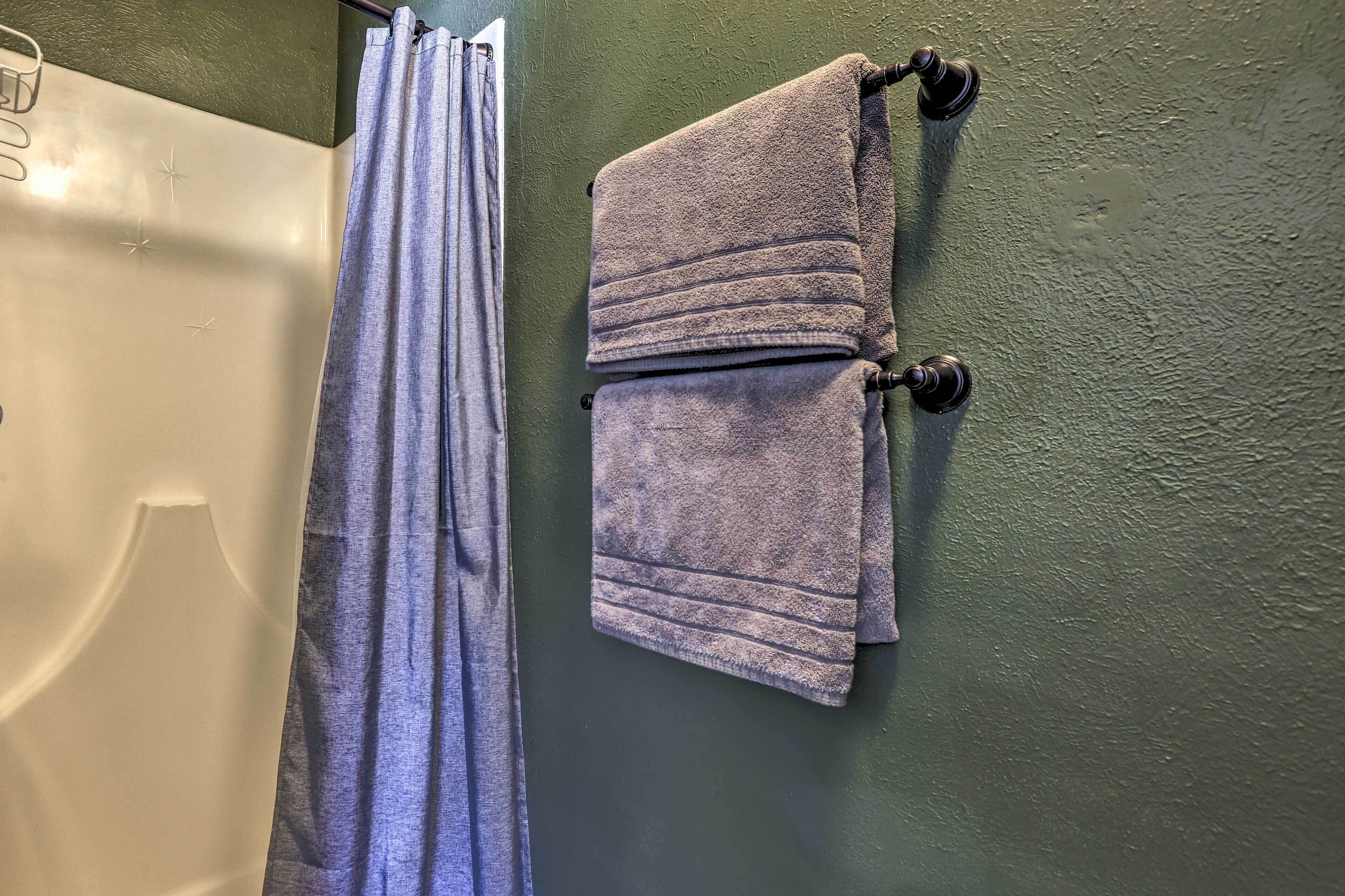 A bathroom with a white bathtub, a blue shower curtain, and a towel rack with a folded towel.