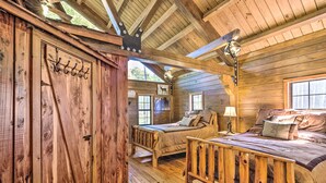A rustic wooden cabin with two bedrooms, each with a wooden bed and a window. - Countryside Cabin Retreat w/ Outdoor Kitchen! (Rienzi)