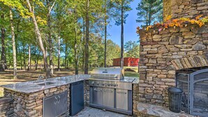 An outdoor kitchen with a stone wall, a grill, and a sink. - Countryside Cabin Retreat w/ Outdoor Kitchen! (Rienzi)