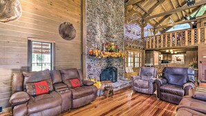 A log cabin interior with a stone fireplace, leather sofas, and a wooden ceiling. - Countryside Cabin Retreat w/ Outdoor Kitchen! (Rienzi)