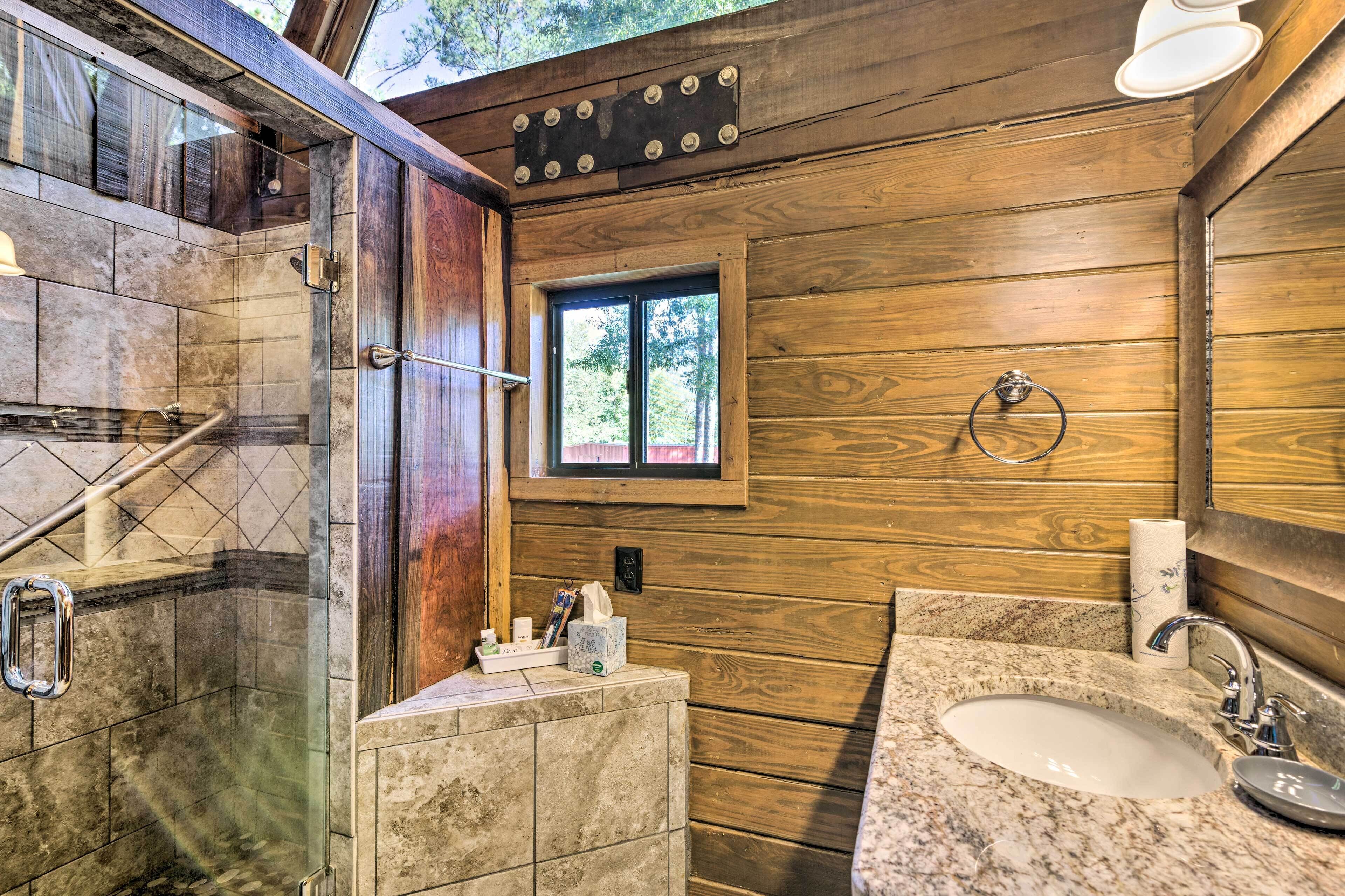 A bathroom with a shower, a sink, and a window.