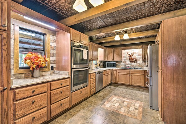 A kitchen with wooden cabinets, stainless steel appliances, and a decorative deer wall. - Countryside Cabin Retreat w/ Outdoor Kitchen! (Rienzi)