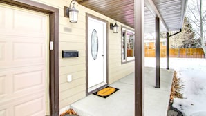 A residential house with a garage door, a front door with a doormat, and a covered porch area. - Cozy Belgrade Home Near Skiing, Hiking & Airport! (Belgrade)
