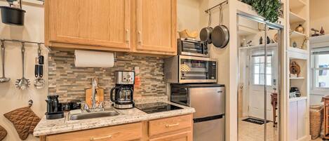 A modern kitchen with wooden cabinets, a stainless steel refrigerator, a built-in oven, and a coffee maker.