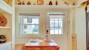 A dining area with a wooden table set for two, two wine glasses, and a bench.