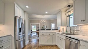 A modern kitchen with white cabinetry, stainless steel appliances, and a wooden floor. - Countryside Cottage w/ Large Yard Near Topeka (Silver Lake)