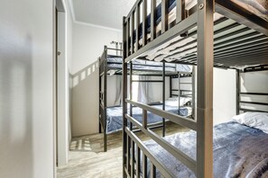 A dormitory room with bunk beds, a wooden floor, and a white door. - Cozy Cassopolis Retreat on Little Fish Lake! (Cassopolis)