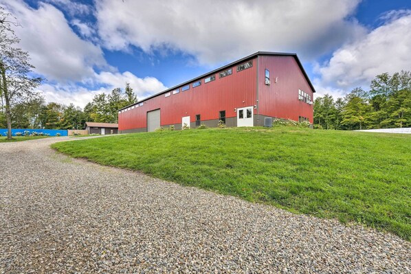 A red industrial building with a gravel driveway and a grassy area in front. - Cozy Cassopolis Retreat on Little Fish Lake! (Cassopolis)