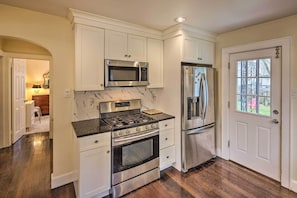 A kitchen with white cabinets, stainless steel appliances, and a marble backsplash.