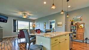 A spacious kitchen with a large island, wooden cabinets, and a view through the window. - Blue Ridge Mountain Rental w/ Hot Tub & Gas Grill! (Marshall)