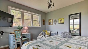 A bedroom with a large bed, a desk, a chair, a dresser, and a window with a view of trees. - Blue Ridge Mountain Rental w/ Hot Tub & Gas Grill! (Marshall)