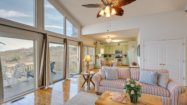 A spacious living area with a large window, a ceiling fan, a dining table, and a kitchen in the background. - Blue Ridge Mountain Golf Resort Home w/ Views! (Roaring Gap)