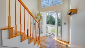 A staircase with wooden balusters leading to a landing, a door with a glass panel, and a view of the outdoors through a window. - Blue Ridge Mountain Golf Resort Home w/ Views! (Roaring Gap)