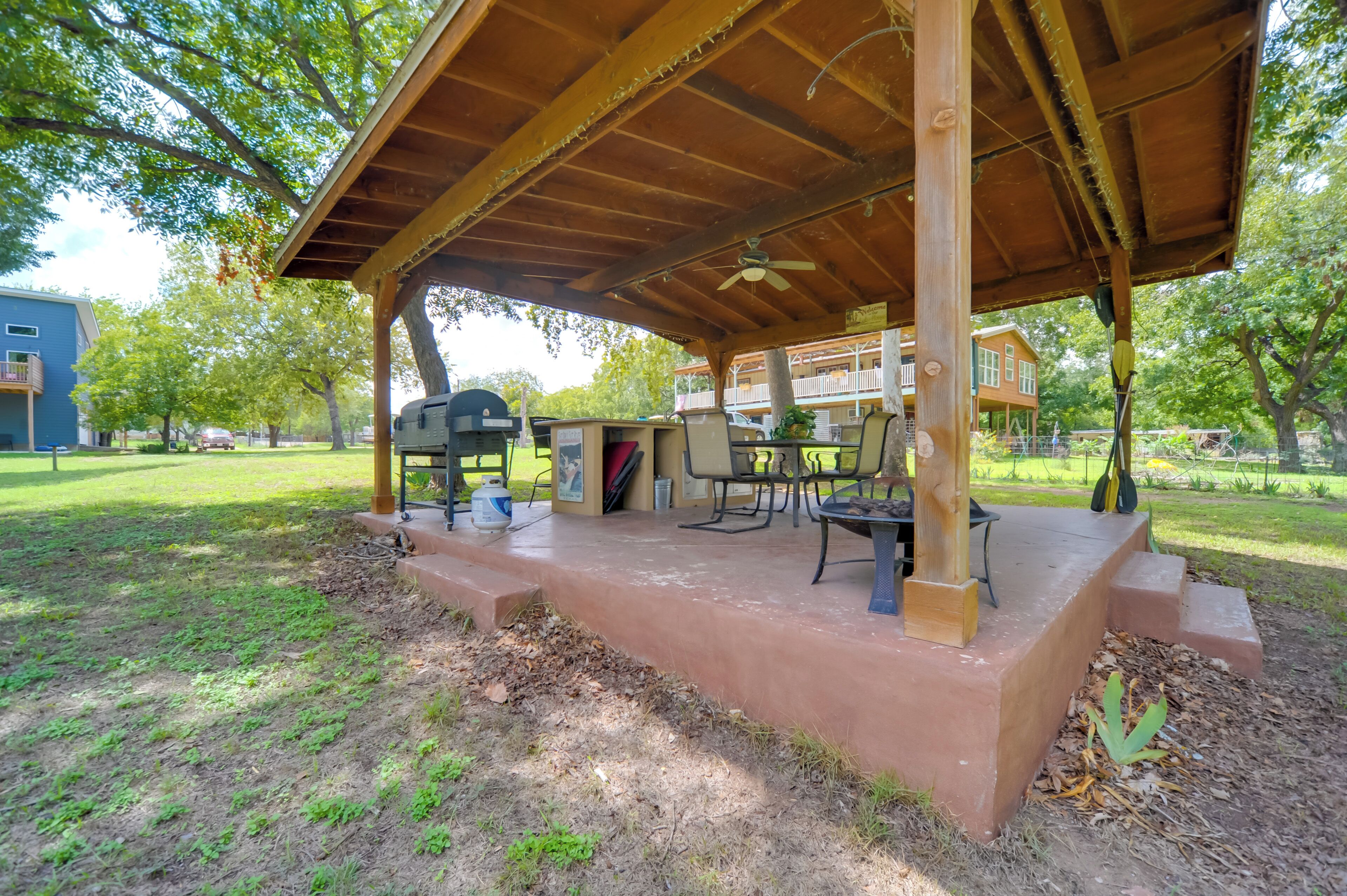 A covered outdoor patio with a grill, chairs, and a table.