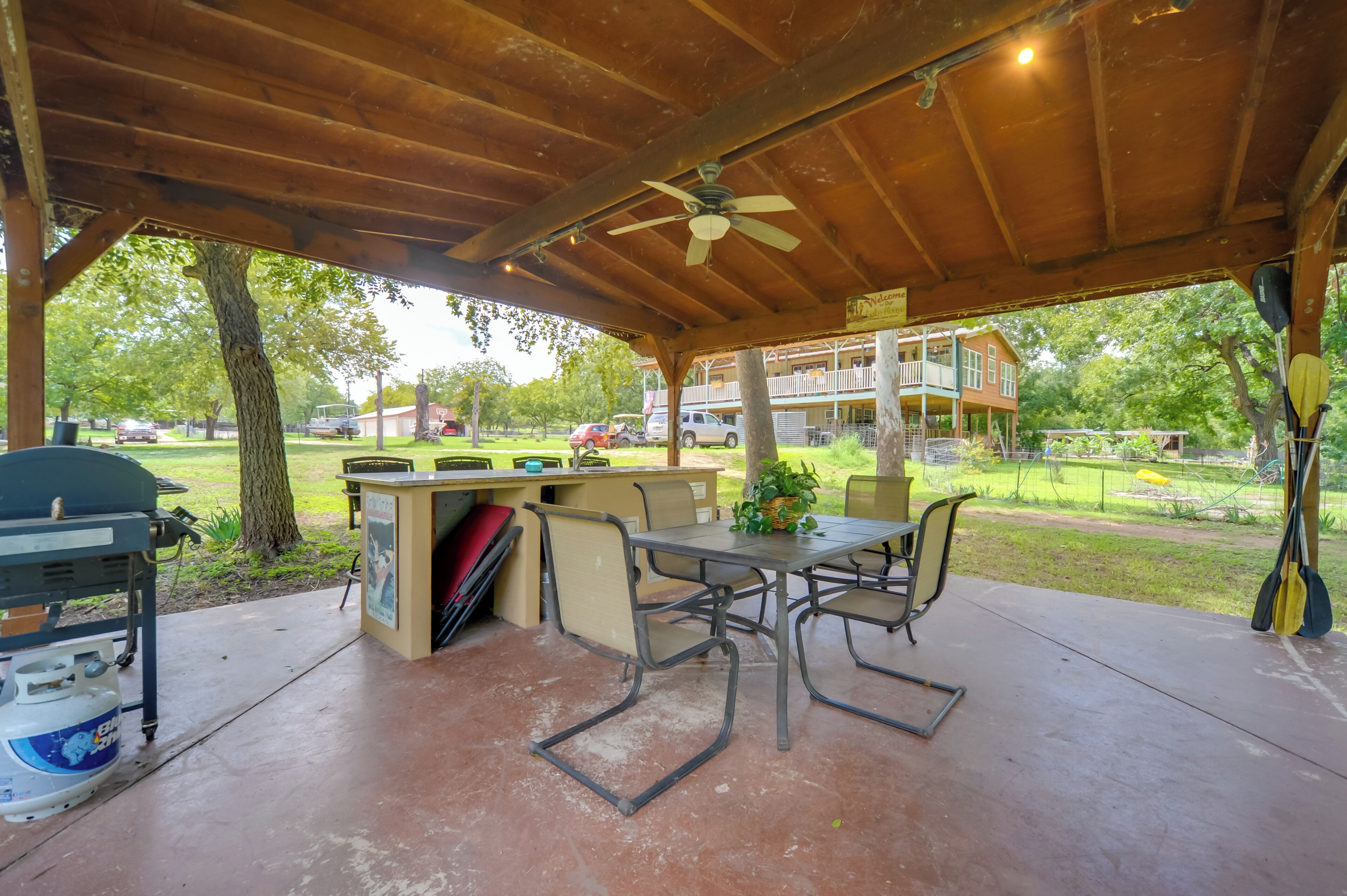 An outdoor covered patio with a table and chairs, a grill, and a water cooler.