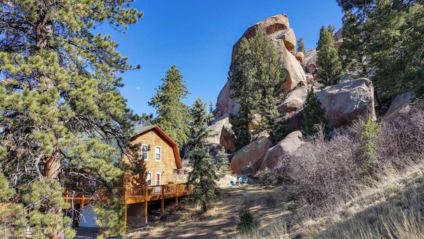 A cabin with a deck, surrounded by pine trees and large boulders. - 'dragons Roost' Cabin w/ Sangre de Cristo Views! (Florissant)