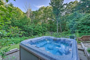 A hot tub in a lush garden with dense trees and a wooden deck. - Game Room & Hot Tub: Pet-friendly Mount Snow Gem (West Dover)
