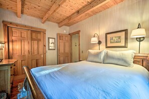A bedroom with a large bed, wooden ceiling beams, two doors, and wall-mounted lamps. - Game Room & Hot Tub: Pet-friendly Mount Snow Gem (West Dover)