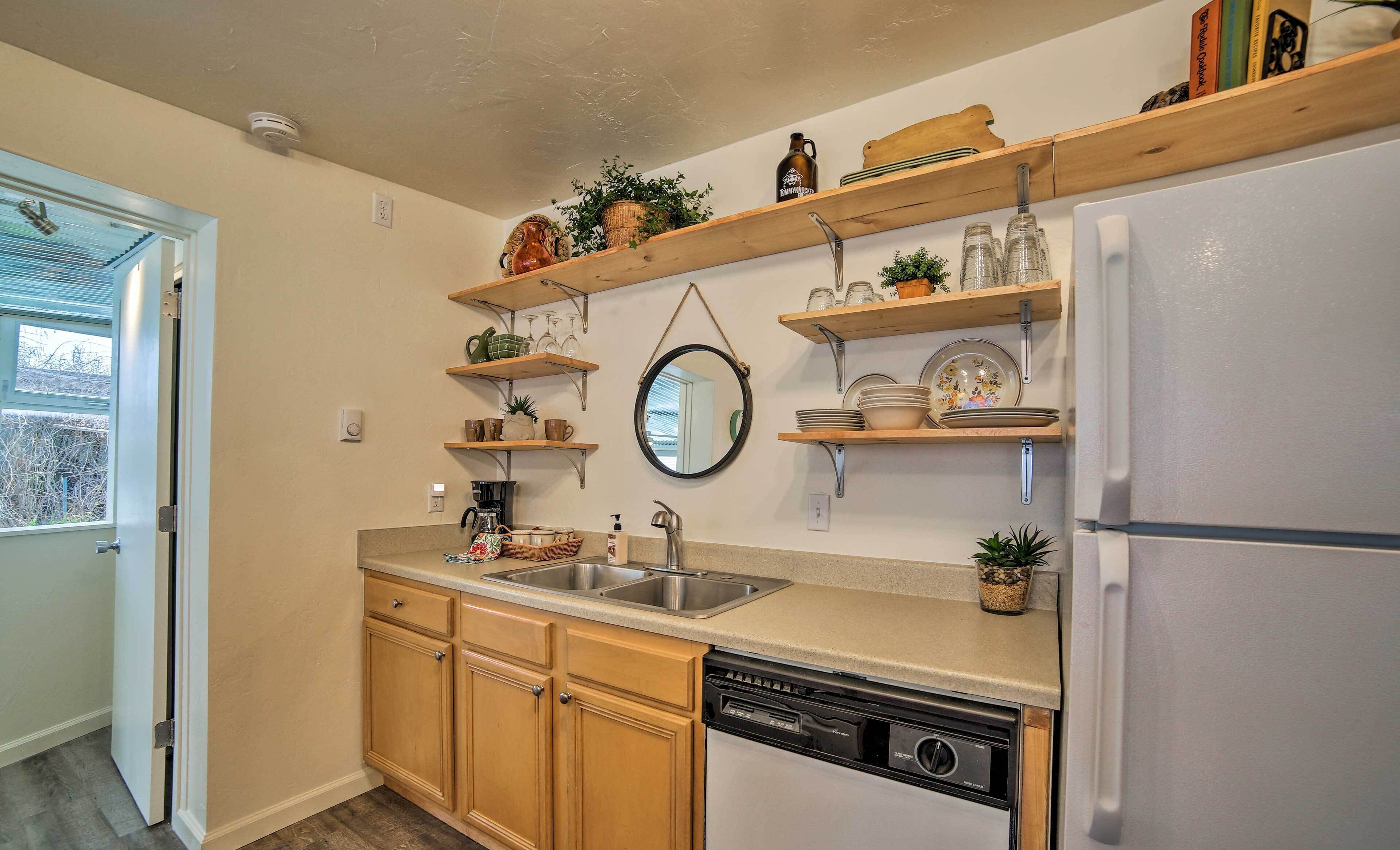 A kitchen with wooden cabinets, a dishwasher, a refrigerator, and wooden shelves with various kitchen items.