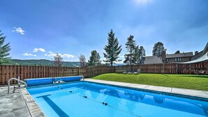 A rectangular swimming pool with a wooden fence and a grassy area in the background. - Big Sky Condo w/ Resort Amenities & Mountain Views (Big Sky)