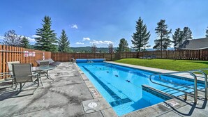 A rectangular swimming pool with a wooden fence and chairs around it. - Big Sky Condo w/ Resort Amenities & Mountain Views (Big Sky)