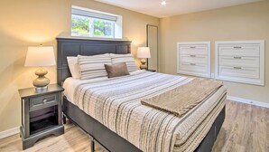Une chambre à coucher comprenant un lit, des tables de chevet, une fenêtre et des tiroirs de rangement intégrés.