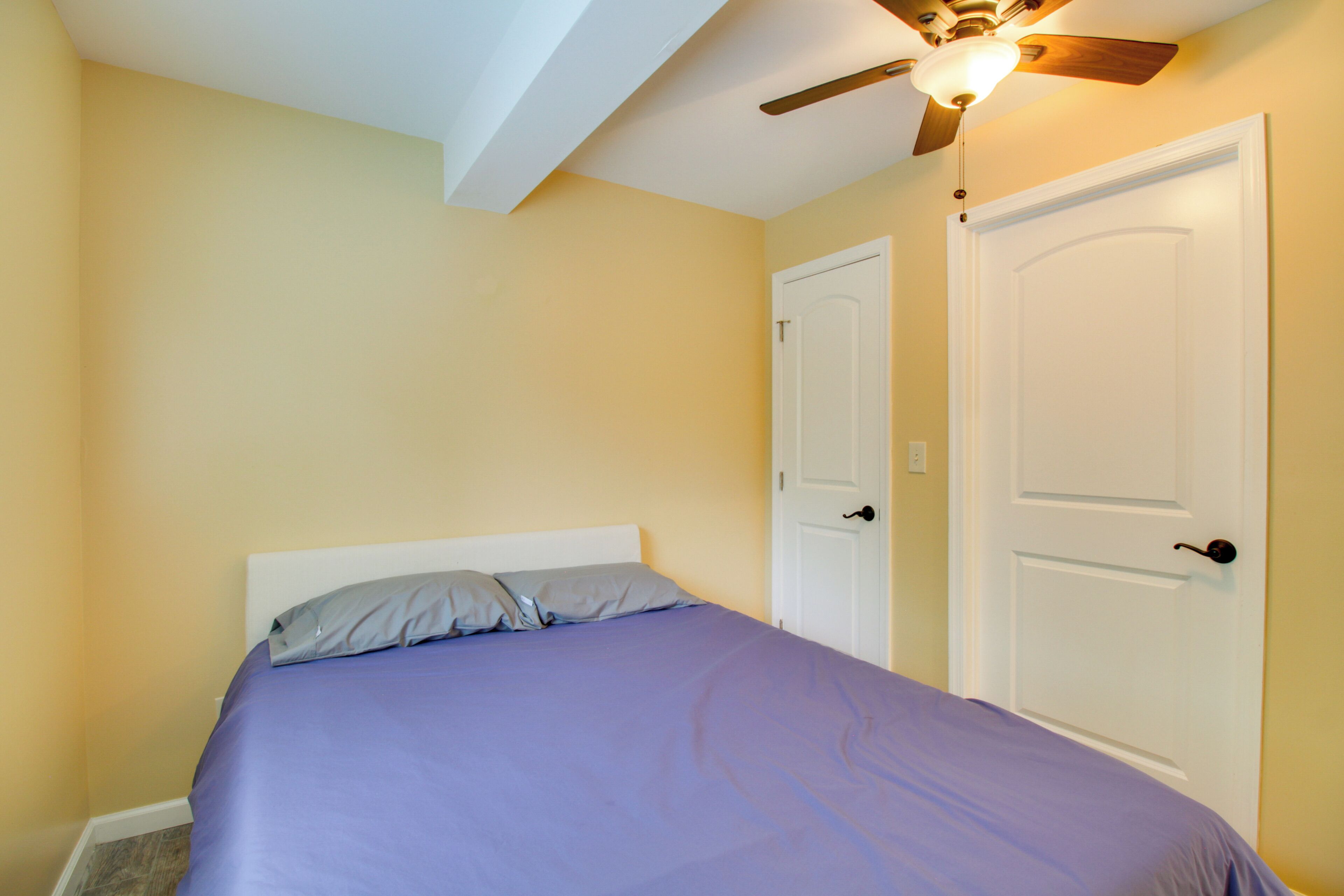Une chambre à coucher avec un lit, deux portes et un ventilateur de plafond.