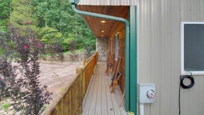 A wooden deck with a stone wall, a window, and a power outlet.