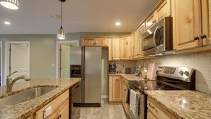 A modern kitchen with granite countertops, stainless steel appliances, wooden cabinets, and a built-in oven.