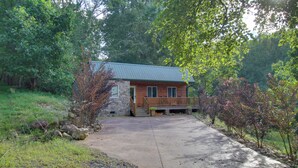 A cabin with a stone foundation, wooden exterior, and a covered porch.
