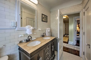 A bathroom with two sinks, a large mirror, and a door leading to another room.