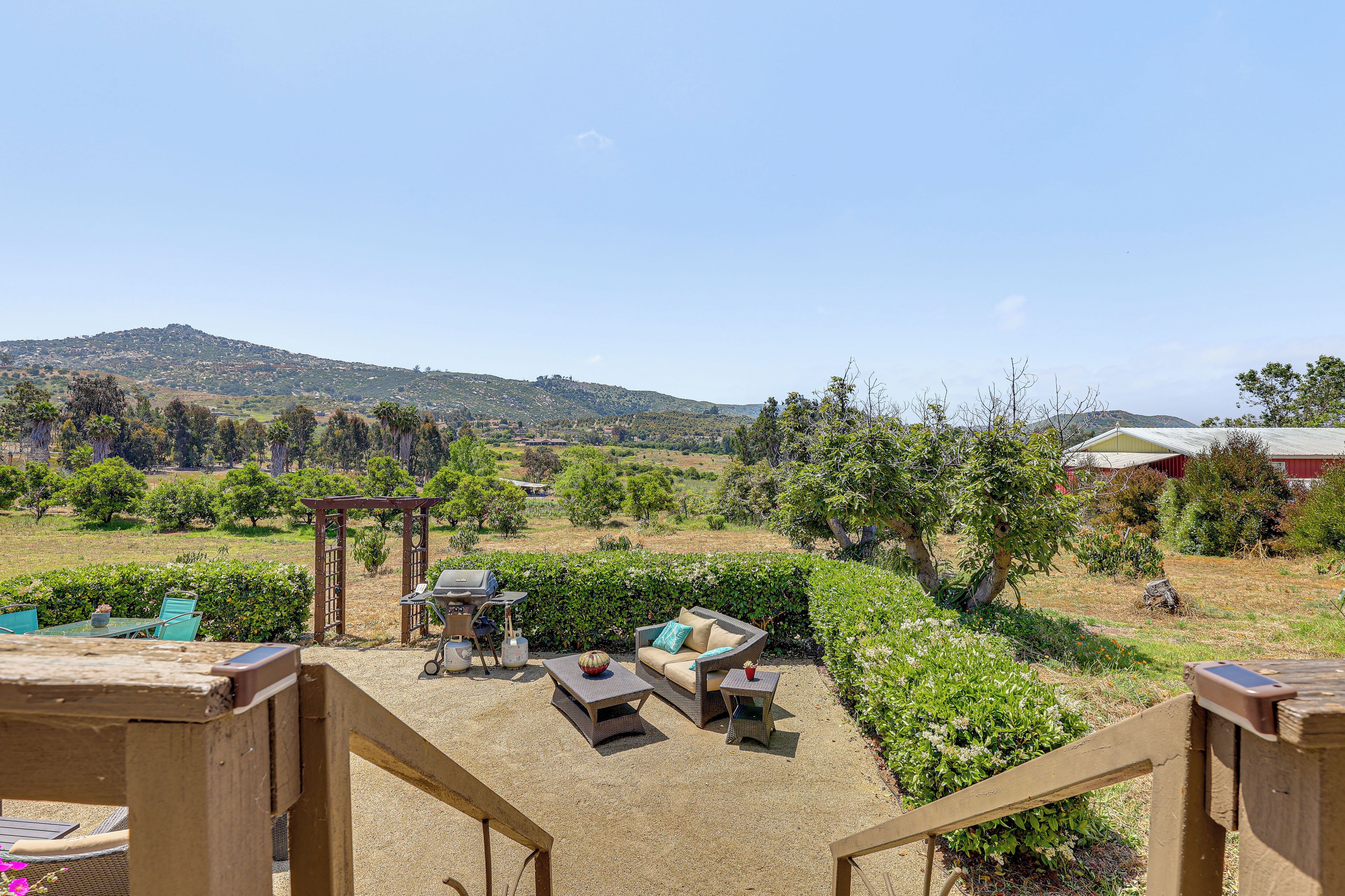 An outdoor patio with a wooden pergola, a barbecue grill, and outdoor furniture.