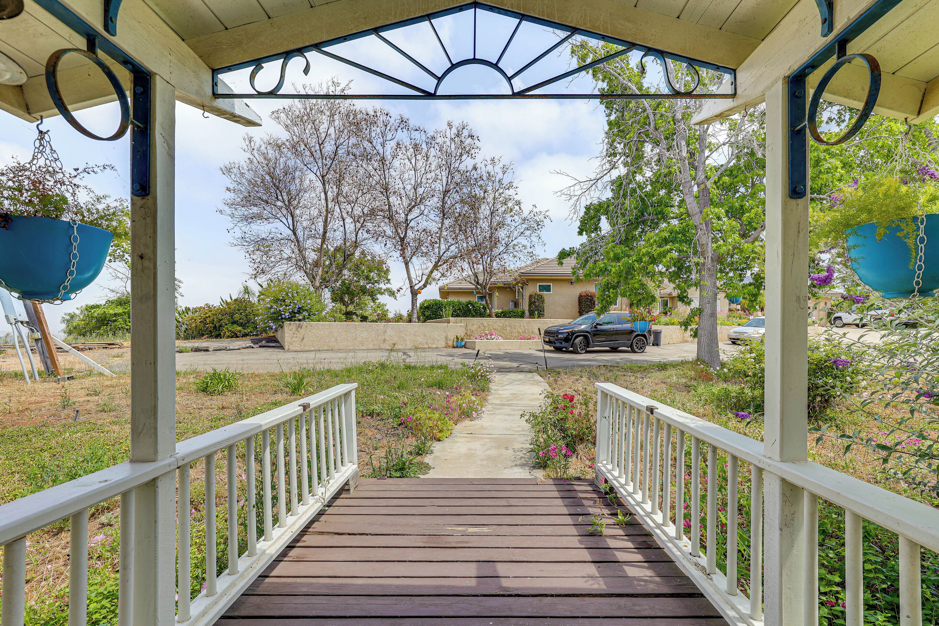 A wooden deck leading to a covered area with a view of a residential street and houses.