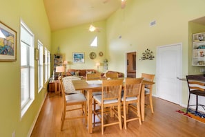 Uma sala de estar ampla, com uma mesa de jantar de madeira e cadeiras, um sofá e um ventilador de teto.