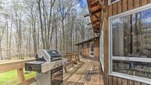 A deck with a grill and a wooden bench, overlooking a forested area. - Walk to Big Bass Lake: Family Home w/ Deck! (Gouldsboro)