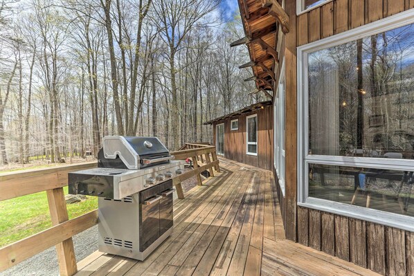 A deck with a grill and a wooden bench, overlooking a forested area. - Walk to Big Bass Lake: Family Home w/ Deck! (Gouldsboro)