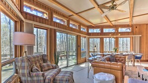 A spacious living area with large windows, a ceiling fan, and a dining area with a table and chairs. - Walk to Big Bass Lake: Family Home w/ Deck! (Gouldsboro)