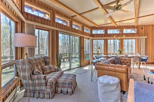 A spacious living area with large windows, a ceiling fan, and a dining area with a table and chairs.