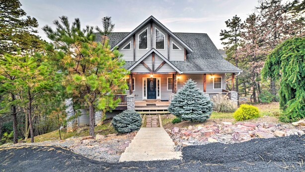 A two-story house with a front porch, a stone foundation, and a well-maintained front yard with trees and shrubs.