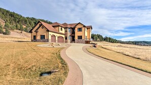 A large, two-story house with a stone foundation and a curved driveway leading to the entrance.