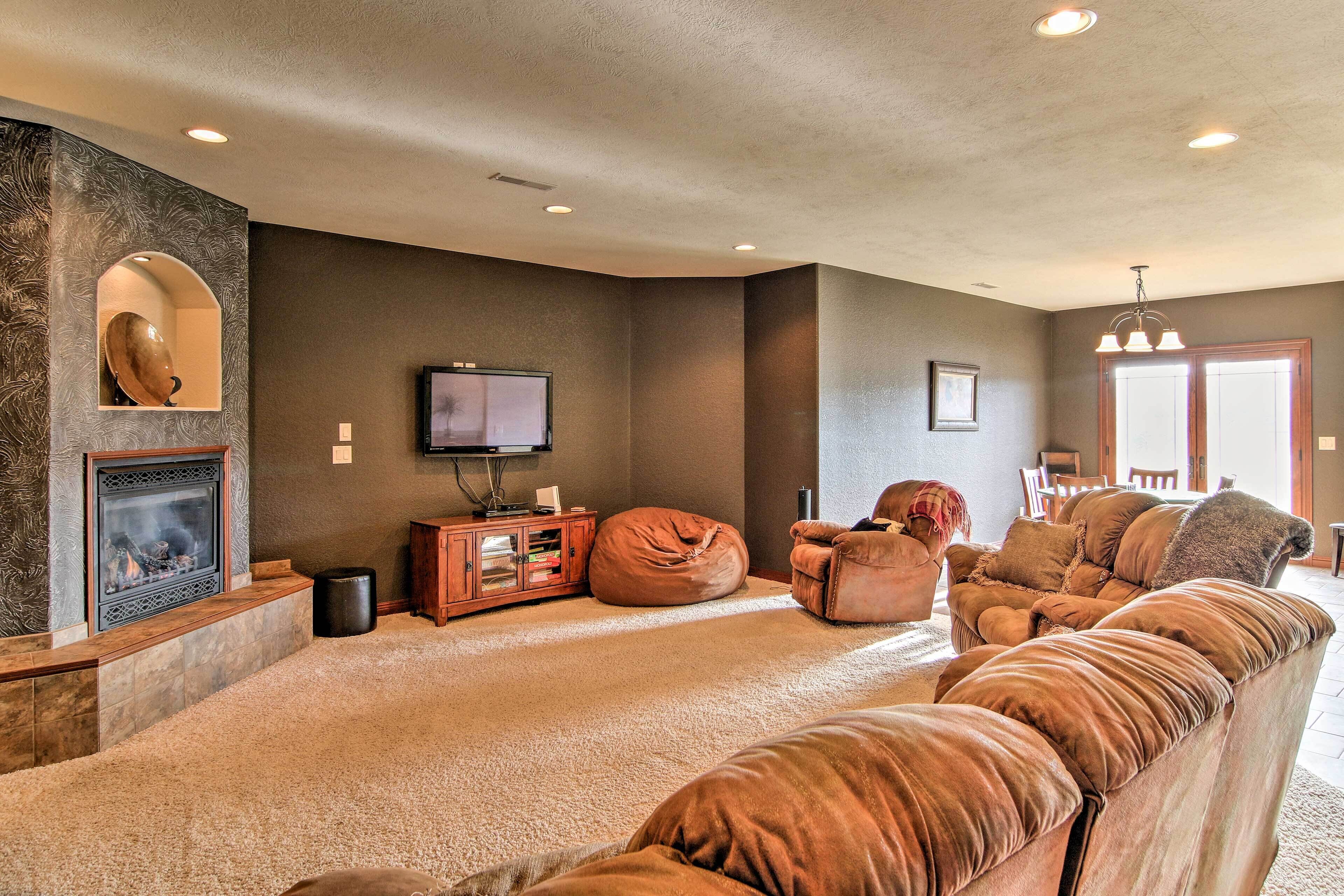 A modern living room with a fireplace, a large sectional sofa, a bean bag, and a television.