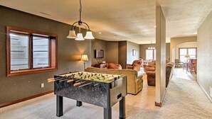 A spacious living room with a foosball table, a sofa, and a television.