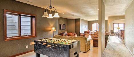 A spacious living room with a foosball table, a sofa, and a television.