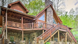 A log cabin with a stone foundation, wooden balconies, and a staircase leading to the upper level. - Hike, Fish & Golf: Burnsville Retreat w/ Deck! (Burnsville)
