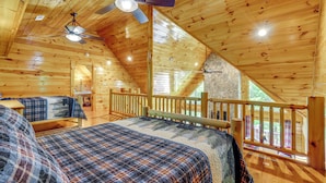 A wooden cabin with a loft bedroom, a dining area, and a stone fireplace. - Hike, Fish & Golf: Burnsville Retreat w/ Deck! (Burnsville)