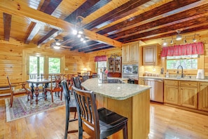 Interior de una cabaña de madera con comedor, cocina y barra.