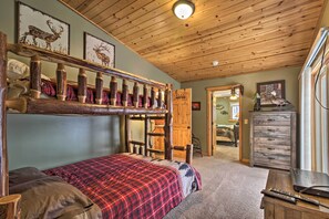 A rustic room with a bunk bed, wooden ceiling, and a dresser with a television. - Dock, Fire Pit & Beach! Expansive Ruth Lake Home (Emily)