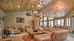 A spacious living room with a large leather sofa, multiple chairs, a wooden coffee table, and a fireplace. - Dock, Fire Pit & Beach! Expansive Ruth Lake Home (Emily)