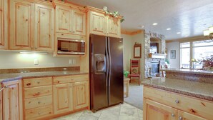Una cocina con armarios de madera, un refrigerador de acero inoxidable, un microondas y encimeras de granito.
