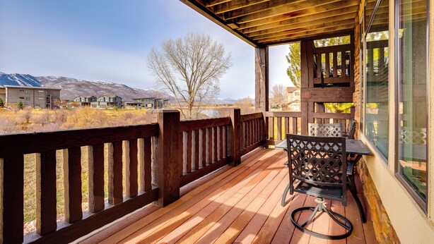 Una terraza de madera con vistas a montañas y edificios al fondo.